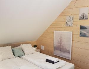 Cama blanca en habitación con paredes de madera en Koniakowo - dom Pinto en Koniaków