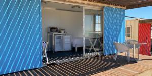 a blue house with a deck with a table and chairs at Kite Basecamp Langebaan in Langebaan