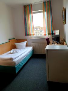 a small bedroom with a bed and a window at Hotel-Pension ODIN in Berlin