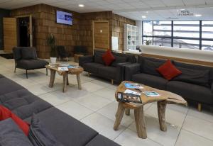 ein Wartezimmer mit Sofas, Tischen und einem TV in der Unterkunft Résidence Prestige Odalys Mendi Alde in La Clusaz