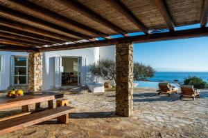 a patio with a table and chairs and the ocean at Zen Residence in Lia beach in Kalafatis