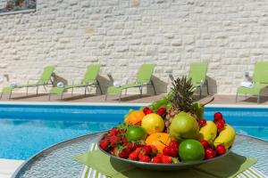 een fruitschaal op een tafel naast een zwembad bij Villa Kogo in Hvar