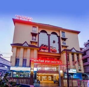 un hotel con una señal roja delante de él en Nextel Inn, Calicut, en Kozhikode