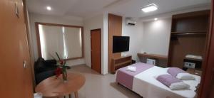 a bedroom with a bed and a table and a tv at Guines Palace Hotel in Patrocínio