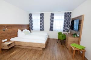 a bedroom with a white bed and a green chair at Ferienbauernhof Köpf in Füssen