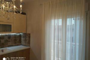 a kitchen with a window with white curtains and a chandelier at Studio Stesi Peraia Thessaloniki s in Perea