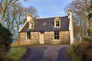 an old stone house on a dirt road at Dunvegan Castle Gardens Cottage in Dunvegan