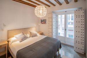 Apartamentos Son de Cadiz في كاديز: غرفة نوم بسرير كبير وثريا