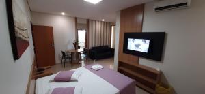 a hotel room with a bed and a flat screen tv at Guines Palace Hotel in Patrocínio