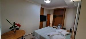 a bedroom with a bed and a table with a vase of flowers at Guines Palace Hotel in Patrocínio