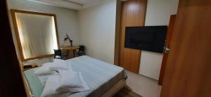 a hotel room with a bed and a television at Guines Palace Hotel in Patrocínio