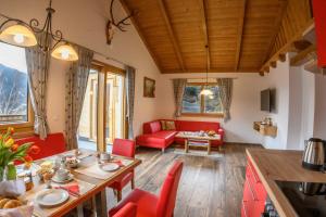 ein Wohnzimmer mit einem Tisch und roten Stühlen in der Unterkunft Chalet Waldhof in Flattach