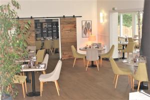 GavrelleにあるLOGIS Hôtel & Restaurant - Le Manoir de Gavrelleのテーブルと椅子が備わるレストラン