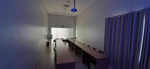 a waiting room with a long table and blue curtains at Guines Palace Hotel in Patrocínio