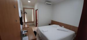 a bedroom with a white bed and a mirror at Guines Palace Hotel in Patrocínio
