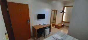 a bedroom with a desk and a bed and a television at Guines Palace Hotel in Patrocínio
