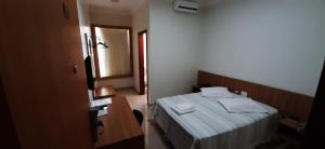 a small bedroom with a bed and a mirror at Guines Palace Hotel in Patrocínio
