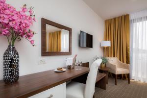 een hotelkamer met een tafel en een vaas met bloemen bij Hotel Perla in Rogoznica