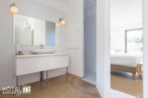 a white bathroom with a sink and a bed at Hôtel 96 in Marseille