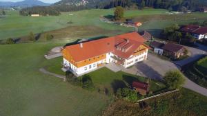 une grande maison avec un toit orange sur un champ verdoyant dans l'établissement Ferienbauernhof Köpf, à Füssen