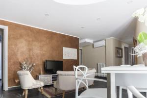 een woonkamer met een tv en een tafel en stoelen bij Elga's Apartment - Your charming stay on Lake Orta in Pettenasco
