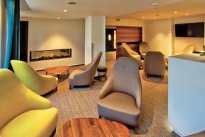 - une salle d'attente avec des chaises, des tables et une cheminée dans l'établissement Logis Hotel Restaurant Spa Beau Site, à Luxeuil-les-Bains