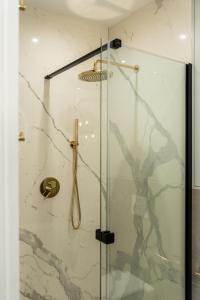 una ducha con puerta de cristal con mango dorado en Apartament w centrum en Gdynia