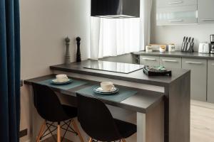 cocina con mesa con 2 tazas y sillas en Apartament w centrum, en Gdynia