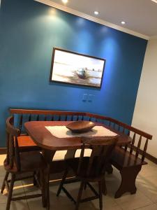 uma mesa de madeira e cadeiras num quarto com uma parede azul em Casa de frente pro mar em Arraial do Cabo em Arraial do Cabo