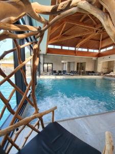 a swimming pool with blue water and a wooden ceiling at Domaine du Ferret Restaurant & Spa in Cap-Ferret
