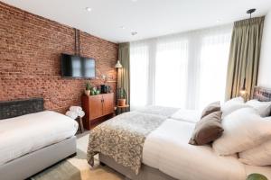 a bedroom with two beds and a brick wall at Hotel Dwars in Amsterdam