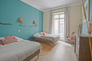 a blue room with two beds and a window at NOCNOC - Le Terracotta in Montpellier