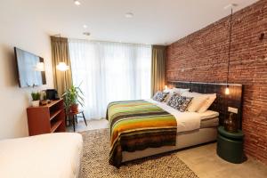a bedroom with a bed and a brick wall at Hotel Dwars in Amsterdam
