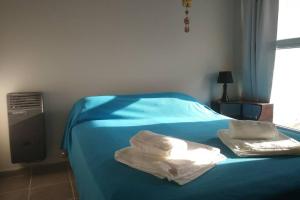 a bed with blue sheets and white towels on it at Departamento temporario Puerto Madryn in Puerto Madryn