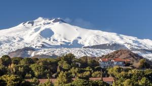 a snow covered mountain with a house in front at Dove nasce il Sole B&B in Nicolosi