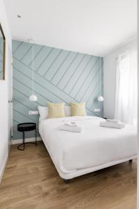 a bedroom with a large white bed with a blue wall at Style Apartments by Olala Homes in Madrid