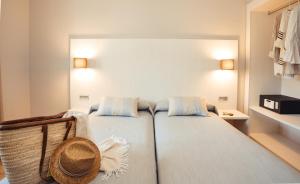 ein Schlafzimmer mit 2 Betten und einem Strohhut in der Unterkunft Minura Cala Galdana & Apartamentos d'Aljandar in Cala Galdana