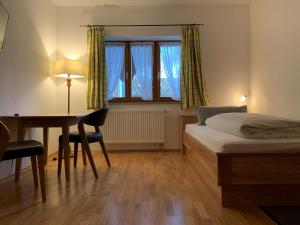 um quarto com uma cama, uma secretária e uma mesa em Zum Dammerbauer em Straßlach-Dingharting