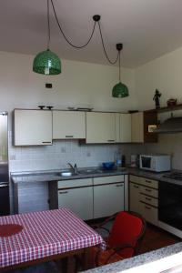 a kitchen with white cabinets and a table with a red chair at La Ca' Nova in Lurago D'Erba 