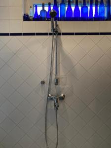 a shower in a bathroom with blue bottles on a wall at Room in Villa Emilia in Espoo