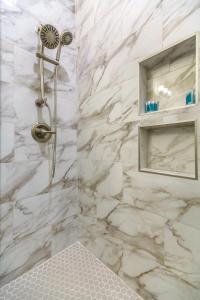 La salle de bains est pourvue d'une douche et de murs en marbre blanc. dans l'établissement Urban Retreat Near French Quarter, à La Nouvelle-Orléans