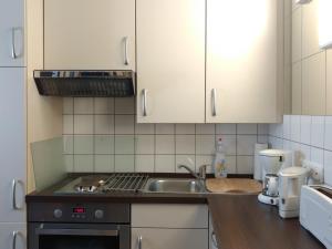 een keuken met een wastafel en een fornuis top oven bij B&B am See Köln - Privatzimmer in Keulen