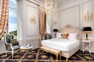 a bedroom with a bed and two chairs and a chandelier at Alexandra Palace - La Maison Younan in Mazières-en-Gâtine