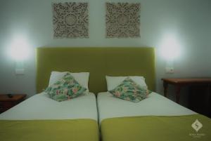Una cama con dos almohadas encima. en Dona Maria en Portalegre
