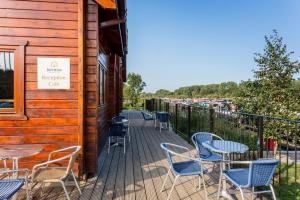 a deck with tables and chairs on a building at Roydon Marina Village Hotel in Roydon