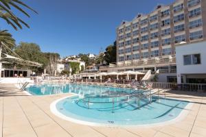 a large swimming pool with a hotel in the background at Minura Cala Galdana & Apartamentos d'Aljandar in Cala Galdana