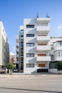 ein weißes Apartmenthaus mit Balkon auf einer Straße in der Unterkunft Mr. Louis - By TLV2GO in Tel Aviv