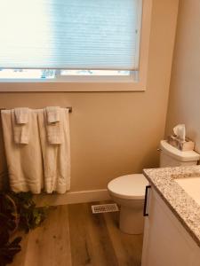 a bathroom with a toilet and a window with towels at Your home away from home in Kelowna