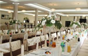 a long table with white chairs and vases with flowers at Motel-Restauracja Ballaton in Chustki