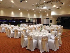 a room full of tables and chairs with white tables and bows at Best Western Ipswich Hotel in Ipswich +70 photos